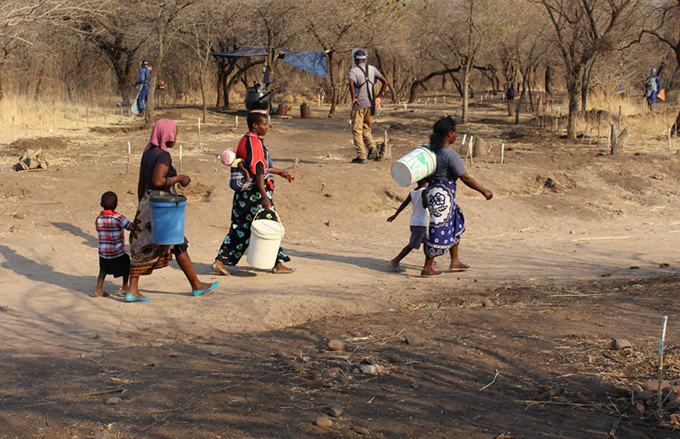 Beneficiaries from Gomo Village, Zimbabwe, on their way to fetch water, pass through an access route on a minefield being cleared by HALO Trust. Photo credit: HALO Trust, 2015